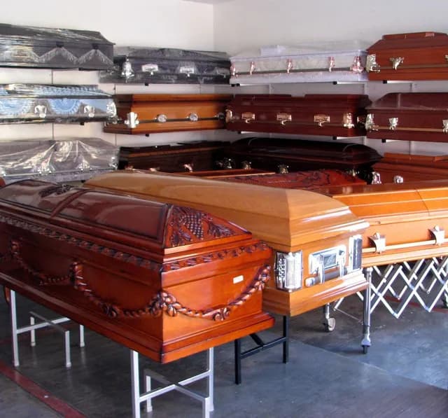 Carved and decorated wooden coffins on display stands at a coffin shop in Wayanad, Kerala