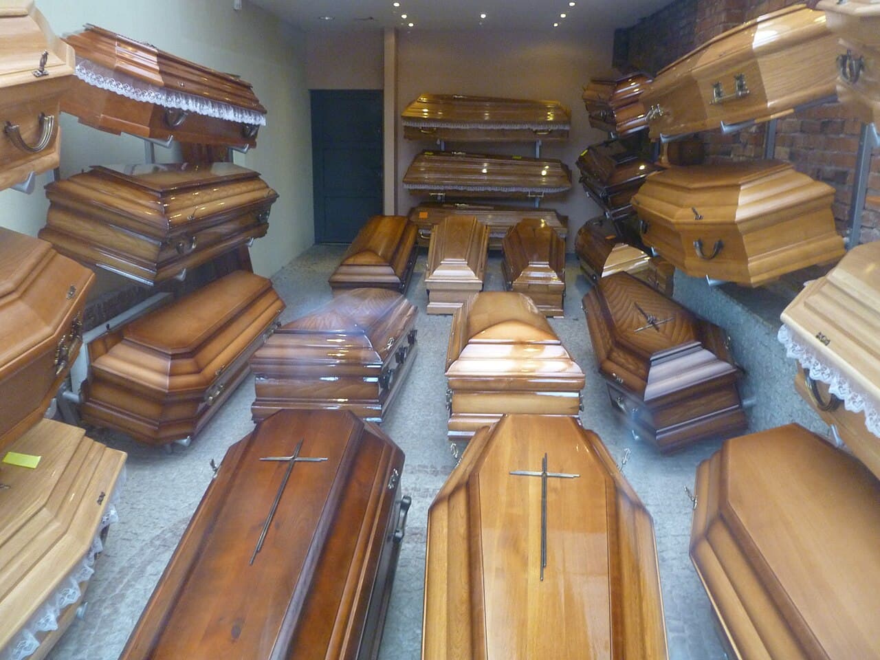 Rows of polished wooden coffins with cross inlays inside the Heaven Funeral Services coffin shop in Wayanad