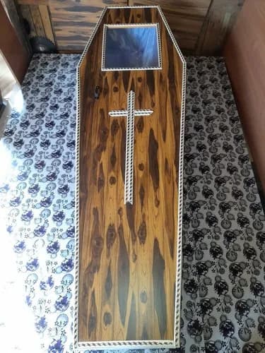 Rosewood coffin with an inlaid white cross and a glass viewing panel, sold at Payyampally and Chennalode in Wayanad