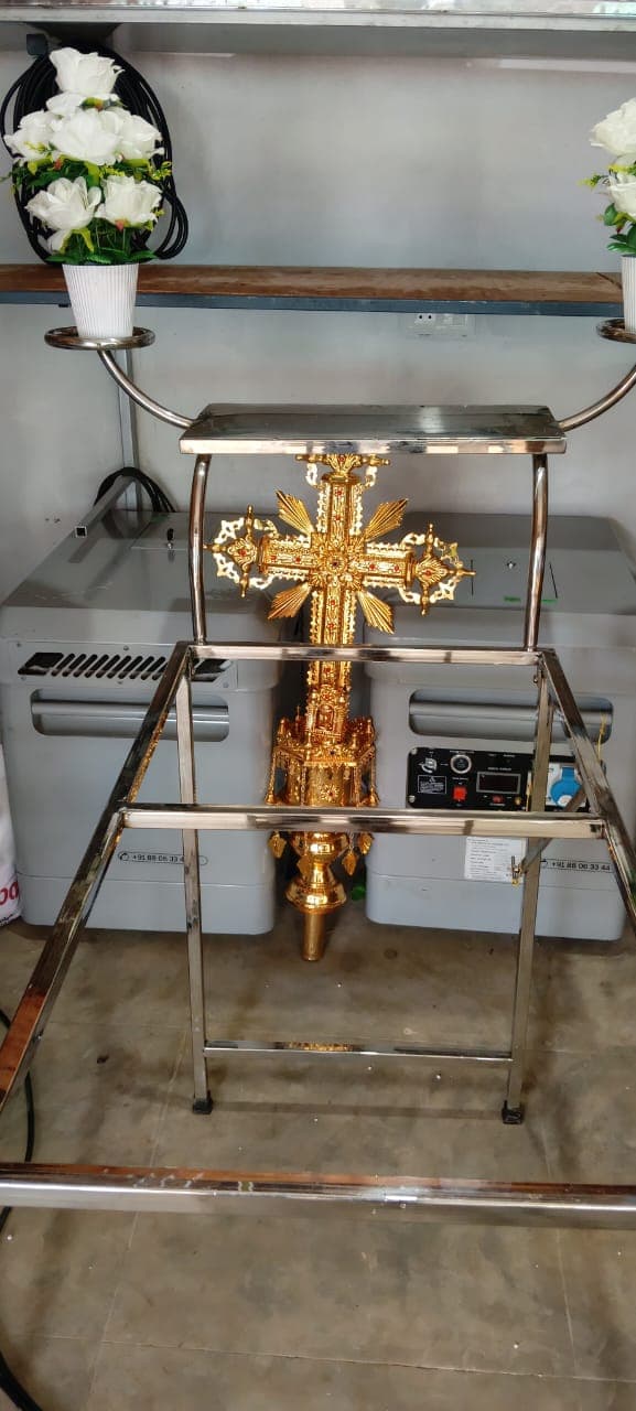 Golden processional cross with white flower arrangements in the showroom